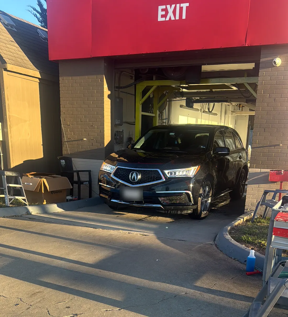 A freshly washed black SUV rolling out of the wash bay under the red Exit canopy